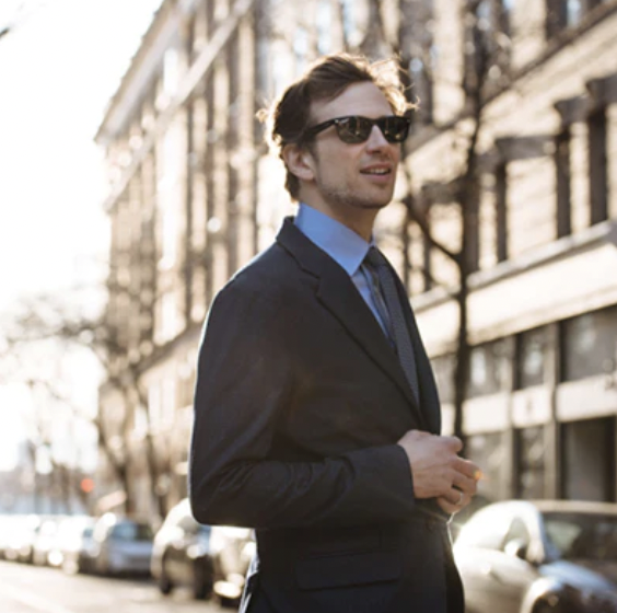 White man in a black suite and tie wearing a blue shirt and tie walking down the street Image